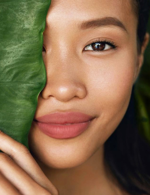 Model with Fresh Clean Skin Make up and Full Lips with Big Green Tropic Leaf Reconstructive